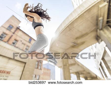 Stock Photo - Caucasian woman jumping in city. Fotosearch