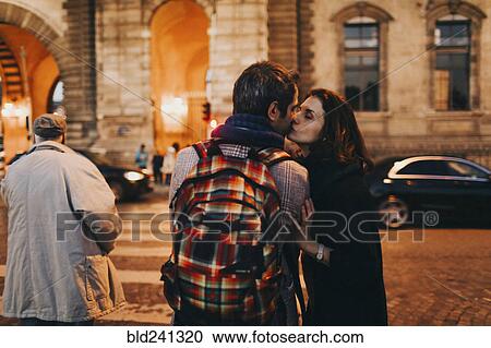 Caucasian woman kissing man on cheek in city at night View Large Photo Image Stock Image - Caucasian woman kissing man on cheek in city at night. Fotosearch
