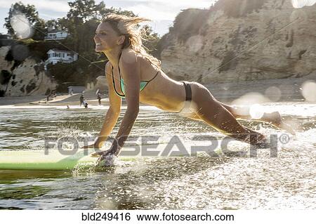 Caucasian woman launching surfboard into ocean View Large Photo Image Stock Photograph - Caucasian woman launching surfboard into ocean. Fotosearch
