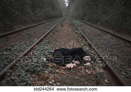 Caucasian woman laying between railroad tracks View Large Photo Image Picture - Caucasian woman laying between railroad tracks. Fotosearch