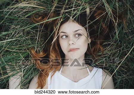 Caucasian woman laying in grass blowing hair off face View Large Photo Image Stock Image - Caucasian woman laying in grass blowing hair off face. Fotosearch