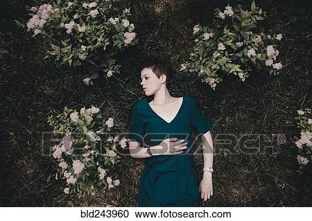Caucasian woman laying in grass near flowers View Large Photo Image Stock Image - Caucasian woman laying in grass near flowers. Fotosearch