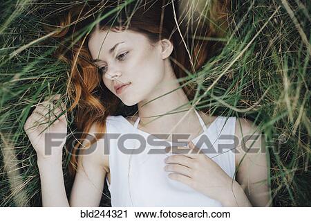 Stock Image - Caucasian woman laying in grass. Fotosearch
