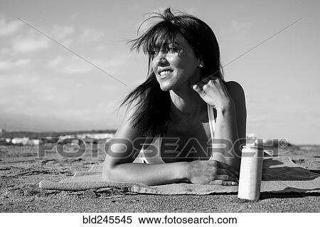 Stock Photography - Caucasian woman laying on beach with can. Fotosearch