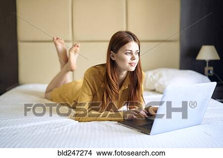 Caucasian woman laying on bed using laptop View Large Photo Image Picture - Caucasian woman laying on bed using laptop. Fotosearch