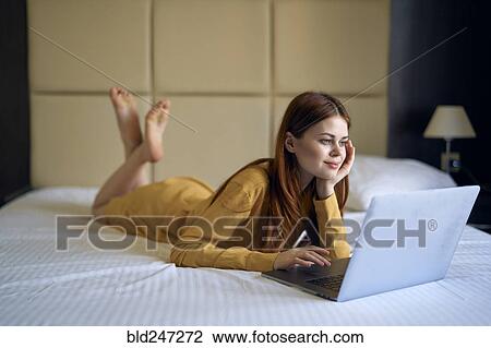 Caucasian woman laying on bed using laptop View Large Photo Image Stock Image - Caucasian woman laying on bed using laptop. Fotosearch