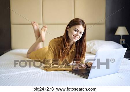 Caucasian woman laying on bed using laptop View Large Photo Image Stock Image - Caucasian woman laying on bed using laptop. Fotosearch