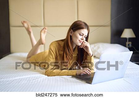 Caucasian woman laying on bed using laptop View Large Photo Image Stock Photography - Caucasian woman laying on bed using laptop. Fotosearch
