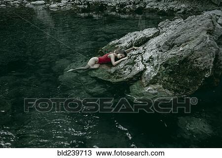 Caucasian woman laying on rocks in pool of water View Large Photo Image Stock Image - Caucasian woman laying on rocks in pool of water. Fotosearch