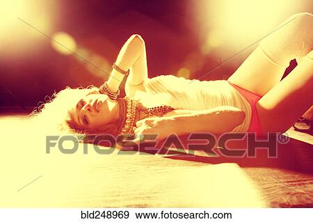 Stock Photo - Caucasian woman laying on sunny floor. Fotosearch