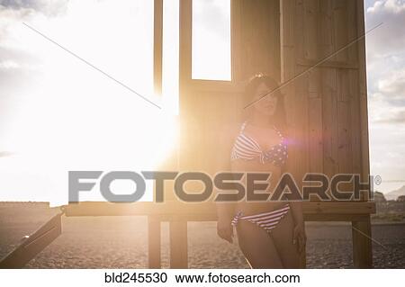 Stock Image - Caucasian woman leaning on cabana on sunny beach. Fotosearch
