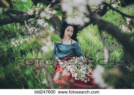 Caucasian woman leaning on tree holding flowers View Large Photo Image Stock Image - Caucasian woman leaning on tree holding flowers. Fotosearch
