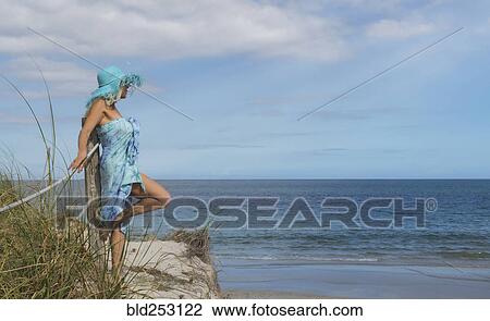 Stock Image - Caucasian woman leaning on wooden post at beach. Fotosearch