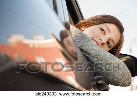 Stock Image - Caucasian woman leaning out car window. Fotosearch