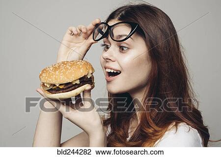 Caucasian woman lifting eyeglasses looking at cheeseburger View Large Photo Image Stock Image - Caucasian woman lifting eyeglasses looking at cheeseburger. Fotosearch