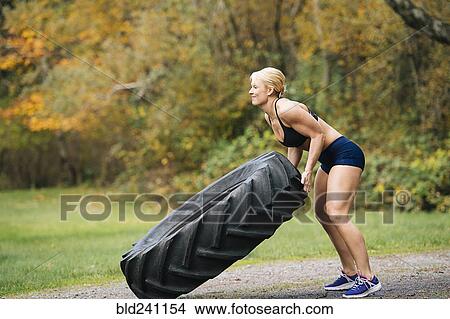 Caucasian woman lifting heavy tire in park View Large Photo Image Picture - Caucasian woman lifting heavy tire in park. Fotosearch