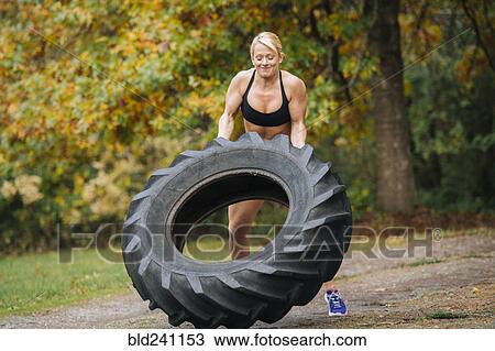 Caucasian woman lifting heavy tire in park View Large Photo Image Stock Image - Caucasian woman lifting heavy tire in park. Fotosearch