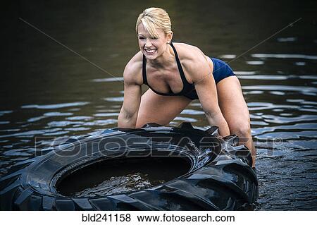 Caucasian woman lifting heavy tire in lake View Large Photo Image Stock Photo - Caucasian woman lifting heavy tire in lake. Fotosearch