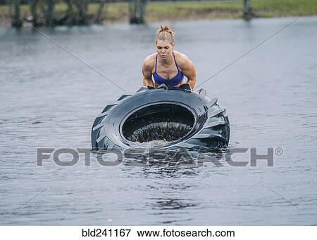 Caucasian woman lifting heavy tire in lake View Large Photo Image Stock Photo - Caucasian woman lifting heavy tire in lake. Fotosearch