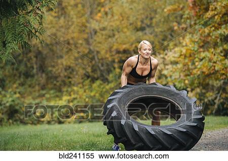 Caucasian woman lifting heavy tire in park View Large Photo Image Stock Photography - Caucasian woman lifting heavy tire in park. Fotosearch