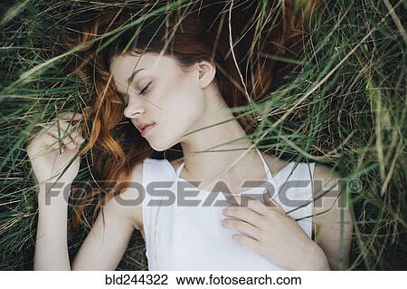 Stock Image - Caucasian woman napping in grass. Fotosearch