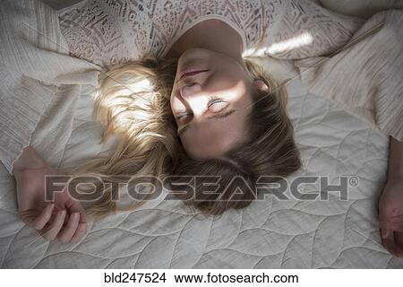 Picture - Caucasian woman napping on bed. Fotosearch