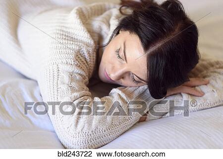 Stock Image - Caucasian woman napping on bed. Fotosearch