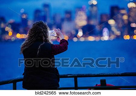 Caucasian woman on boat photographing urban waterfront with cell phone View Large Photo Image Stock Photography - Caucasian woman on boat photographing urban waterfront with cell phone. Fotosearch