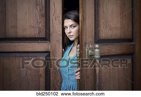 Stock Image - Caucasian woman opening wooden door. Fotosearch