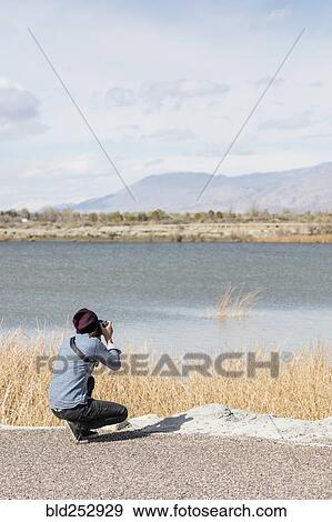 Caucasian woman photographing mountains at river View Large Photo Image Stock Photo - Caucasian woman photographing mountains at river. Fotosearch