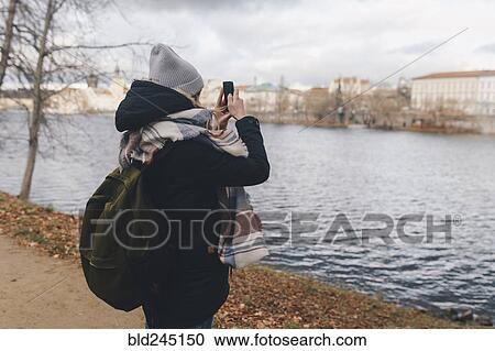Caucasian woman photographing river with cell phone View Large Photo Image Stock Image - Caucasian woman photographing river with cell phone. Fotosearch