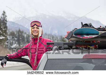 Stock Image - Caucasian woman posing at car with snowboards. Fotosearch