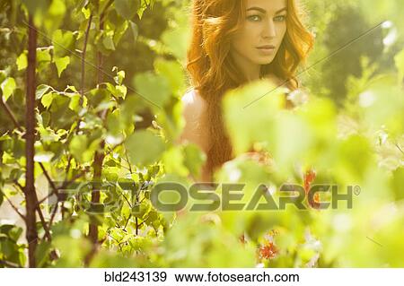 Caucasian woman posing behind foliage View Large Photo Image Stock Photo - Caucasian woman posing behind foliage. Fotosearch