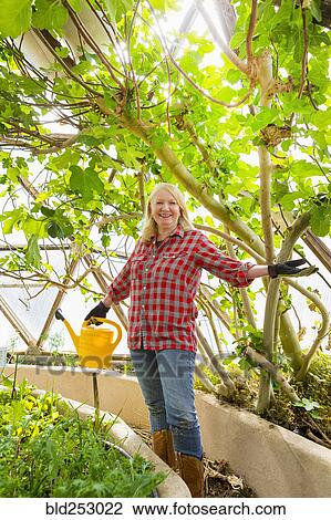 Stock Image - Caucasian woman posing in greenhouse. Fotosearch