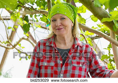 Stock Photo - Caucasian woman posing in greenhouse. Fotosearch