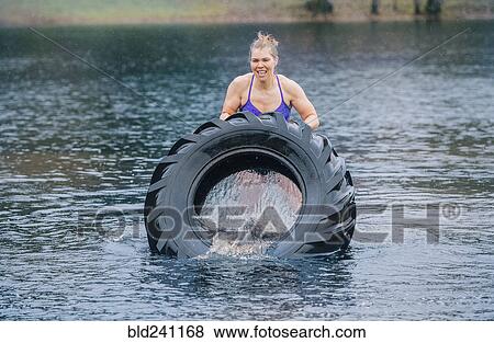Caucasian woman pushing heavy tire in lake View Large Photo Image Stock Photo - Caucasian woman pushing heavy tire in lake. Fotosearch