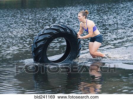 Caucasian woman pushing heavy tire in lake View Large Photo Image Stock Photo - Caucasian woman pushing heavy tire in lake. Fotosearch