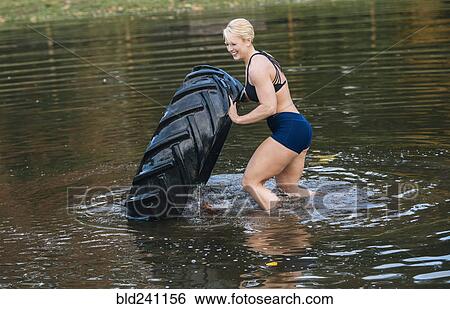 Caucasian woman pushing heavy tire in lake View Large Photo Image Stock Photograph - Caucasian woman pushing heavy tire in lake. Fotosearch