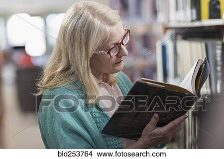 Caucasian woman reading book in library View Large Photo Image Picture - Caucasian woman reading book in library. Fotosearch
