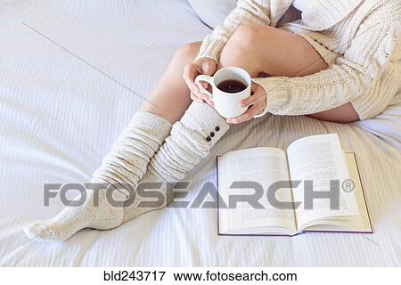 Caucasian woman reading book on bed and drinking coffee View Large Photo Image Stock Photo - Caucasian woman reading book on bed and drinking coffee. Fotosearch