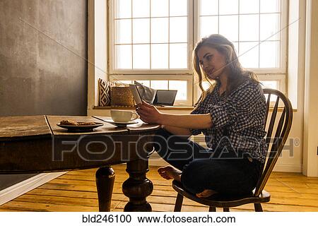 Stock Image - Caucasian woman reading digital tablet at table. Fotosearch