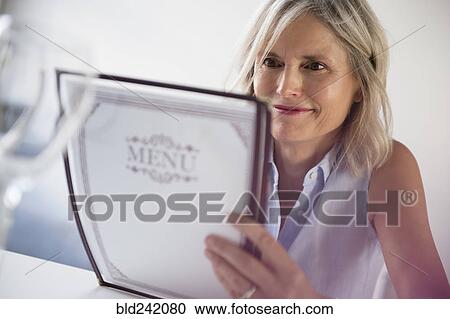 Stock Image - Caucasian woman reading menu in restaurant. Fotosearch