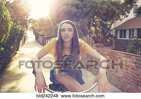 Stock Photo - Caucasian woman riding bicycle in alley. Fotosearch