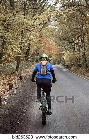 Caucasian woman riding bicycle on forest road View Large Photo Image Stock Image - Caucasian woman riding bicycle on forest road. Fotosearch