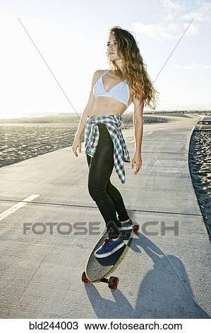 Caucasian woman riding skateboard on path at beach View Large Photo Image Stock Image - Caucasian woman riding skateboard on path at beach. Fotosearch