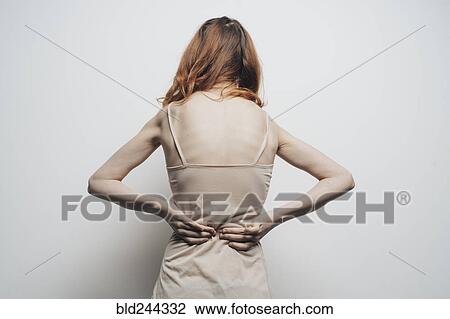Stock Image - Caucasian woman rubbing lower back. Fotosearch