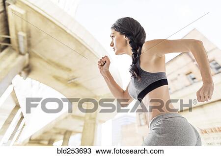 Stock Image - Caucasian woman running in city. Fotosearch