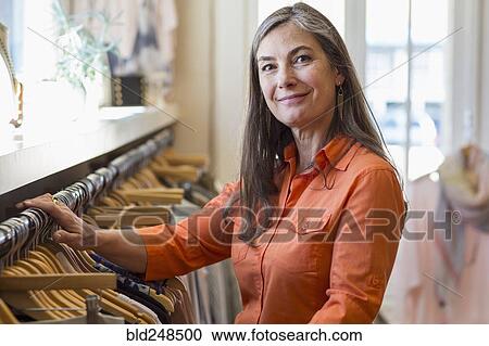 Stock Image - Caucasian woman shopping at clothing store. Fotosearch