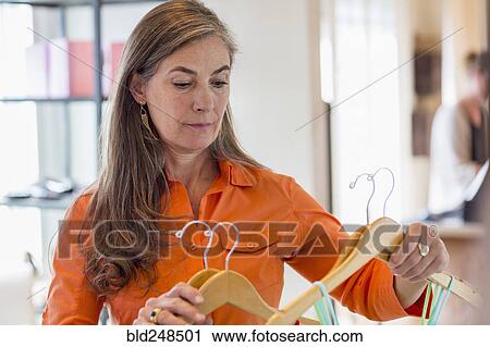 Stock Image - Caucasian woman shopping at clothing store. Fotosearch