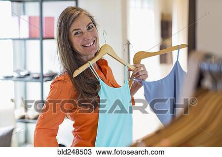 Stock Image - Caucasian woman shopping at clothing store. Fotosearch